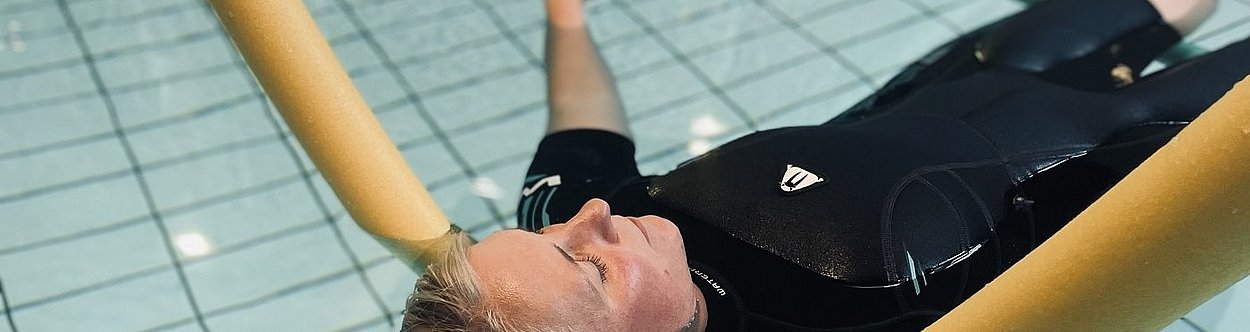 Frau auf Pool Nudel treibt im Wasser