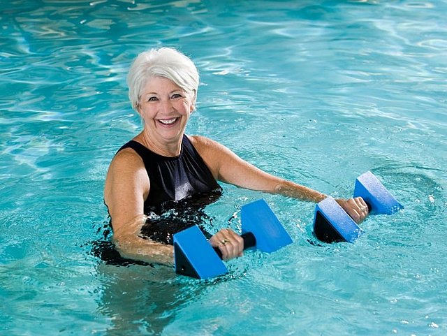 Ältere Frau mit Hanteln im Wasser